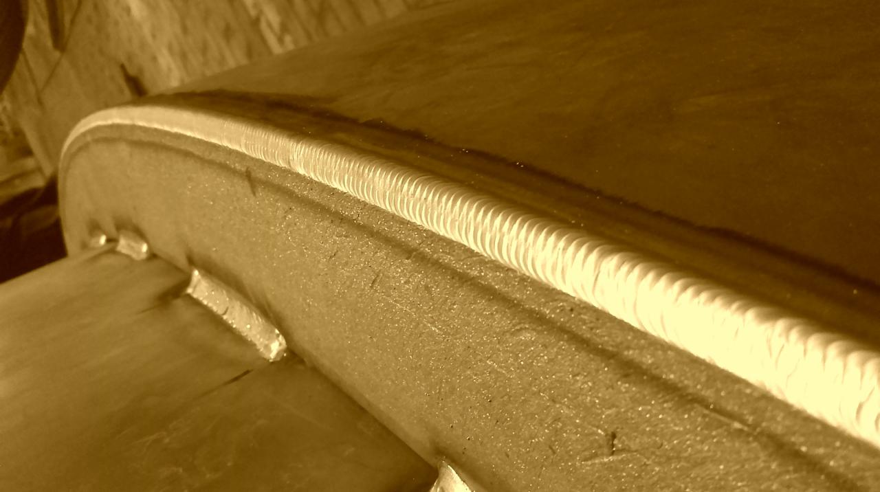 Szczegółowe ujęcie świeżo wykonanego spoiny na metalowej konstrukcji, widoczne ślady po procesie łączenia.