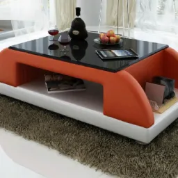 Nowoczesny stolik kawowy z pomarańczowymi, tapicerowanymi bokami, czarnym szklanym blatem, białym korpusem i brązowym dywanem shag, na którym stoi, z winem, kieliszkami, owocami i tabletem na blacie