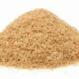 Kopuła jasnobrązowych otrębów zbożowych na białym tle, oświetlona z góry, ukazująca drobną strukturę i nieregularny kształt.