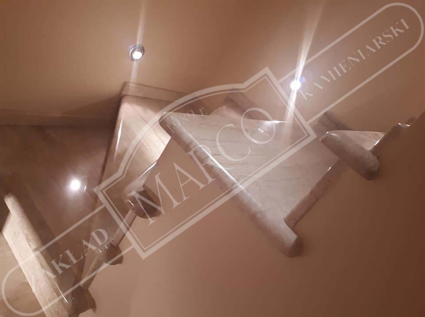 Marmurowe schody wewnętrzne z oświetleniem punktowym w suficie, nałożone logo firmy Zakład Kamieniarski Marco.