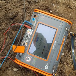 EMI GROUP - Miernik Sonel MPI-540 na ziemi z podłączonymi przewodami, wskazujący rezystancję 3,02 Ω. Urządzenie używane do pomiarów elektrycznych, widoczne złącza i ekran.