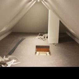 Usługi Ogólnobudowlane Suchecki Dariusz - Poddasze z wykończonymi ścianami i sufitem, widoczne listwy i resztki materiałów po remoncie, otwór w podłodze z widocznymi schodami.