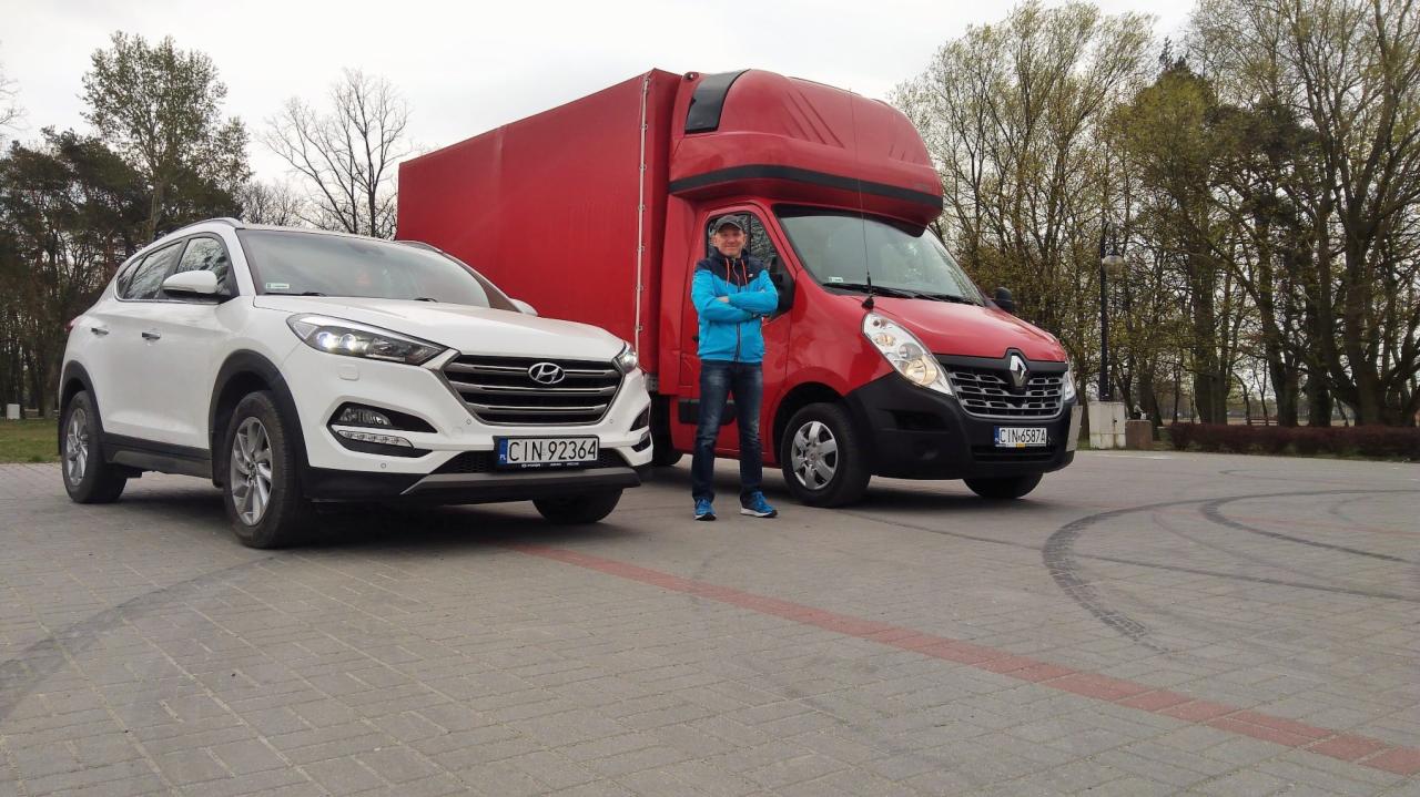 Mężczyzna w niebieskiej kurtce stoi między białym SUV-em Hyundai Tucson a czerwonym busem Renault Master z zabudową kontenerową.