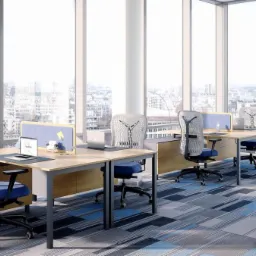 Nowoczesne biuro z biurkami z przegrodami, ergonomicznymi krzesłami, szafkami na dokumenty i niszczarką, z widokiem na miasto przez duże okna.