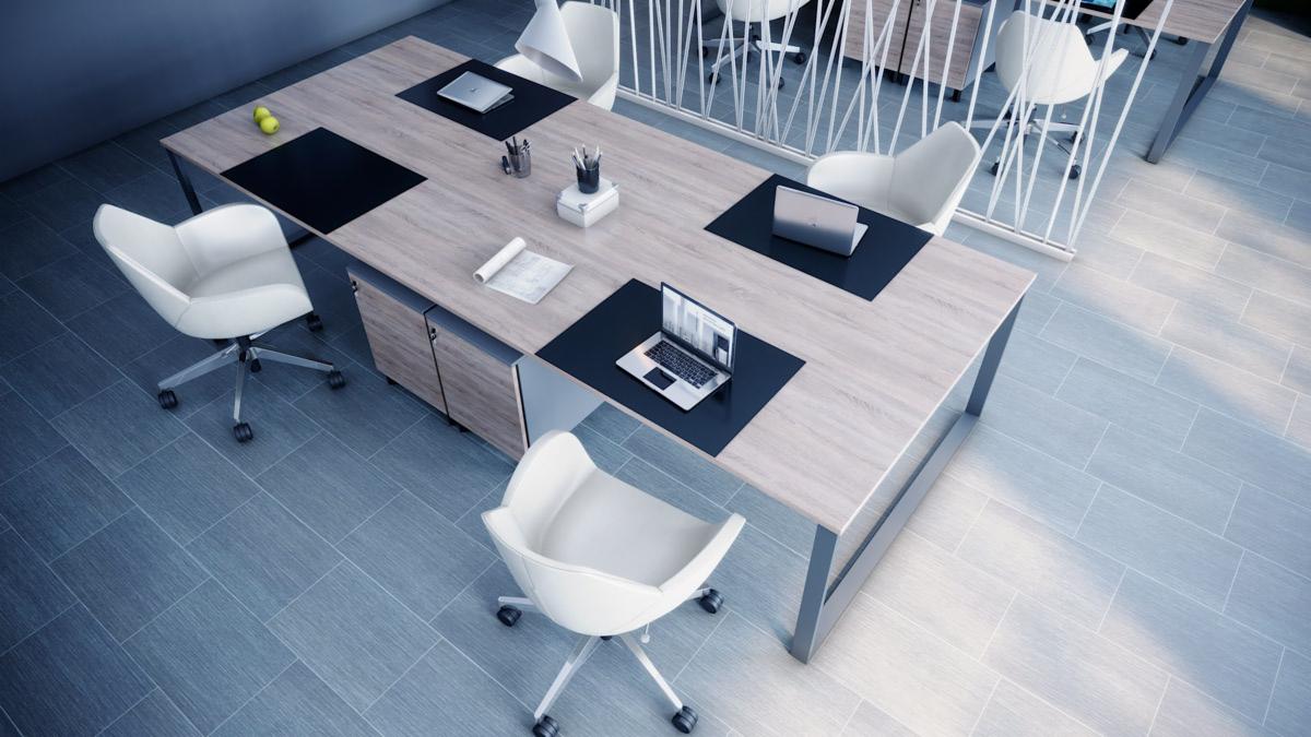 Wnętrze biura z dużym stołem konferencyjnym z blatem w odcieniach drewna, wyposażonym w czarne podkładki, laptopy, przybory biurowe i dokumenty, otoczonym białymi krzesłami obrotowymi na kółkach...