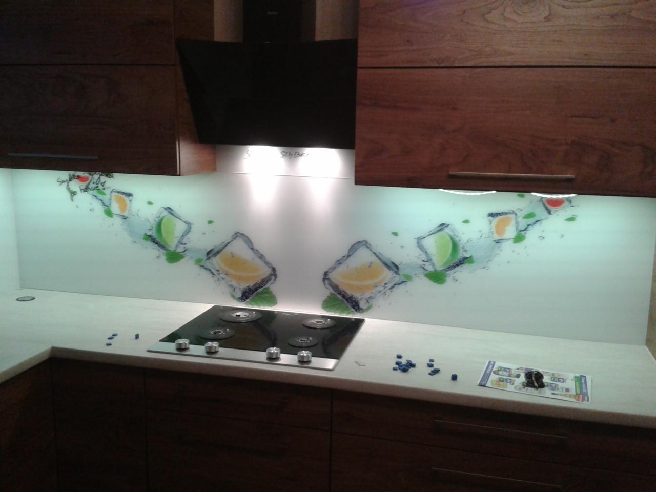 Szklany panel kuchenny z motywem kostek lodu z owocami cytrusowymi, zamontowany nad płytą grzewczą w kuchni z drewnianymi szafkami.