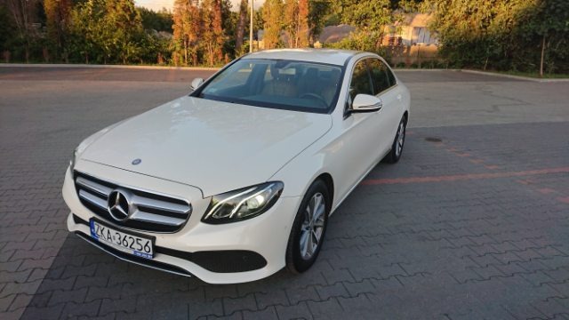 Biały Mercedes-Benz klasy E, widok z przodu, zaparkowany na kostce brukowej, z widoczną tablicą rejestracyjną ZKA 36256.