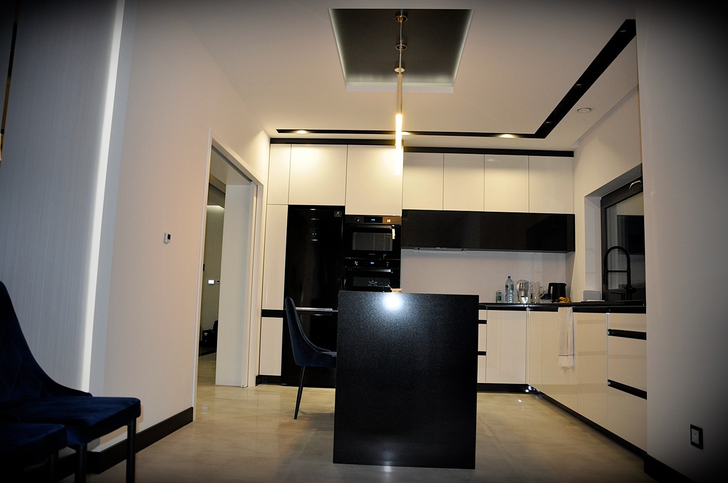 Nowoczesna kuchnia w czarno-białej kolorystyce z wyspą, oświetleniem LED i minimalistycznym designem.