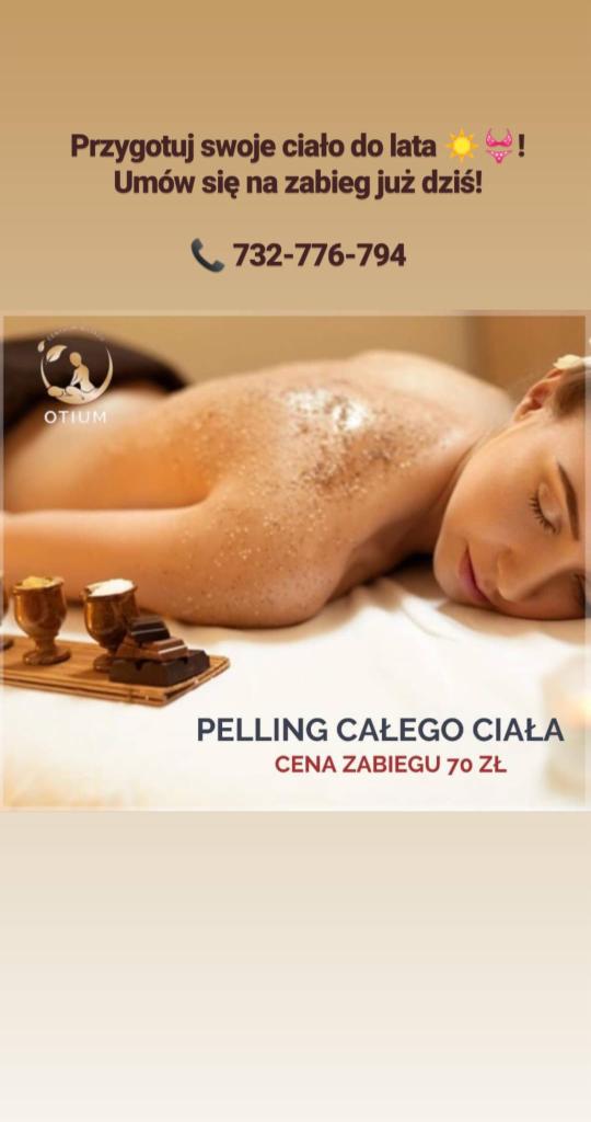 Kobieta leżąca na brzuchu podczas zabiegu peelingu całego ciała, widoczne drobinki peelingu na skórze pleców, obok drewniana taca z miseczkami i kawałkami czekolady, logo salonu OTIUM w lewym...