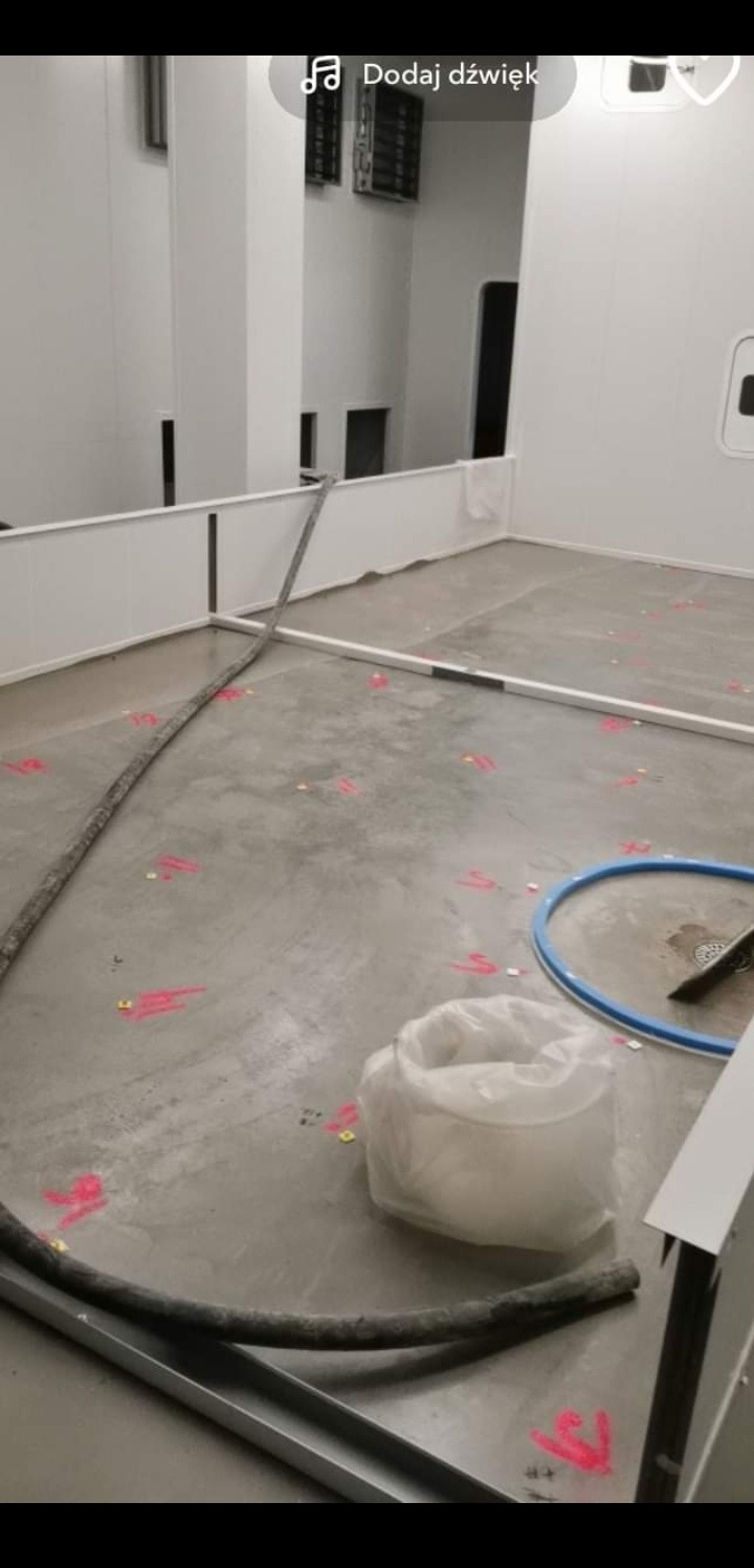 Przygotowanie podłoża w Bierzwniku: Wylewka samopoziomująca z zaznaczonymi punktami pomiarowymi, widoczny worek z zaprawą i wąż do podawania mieszanki.