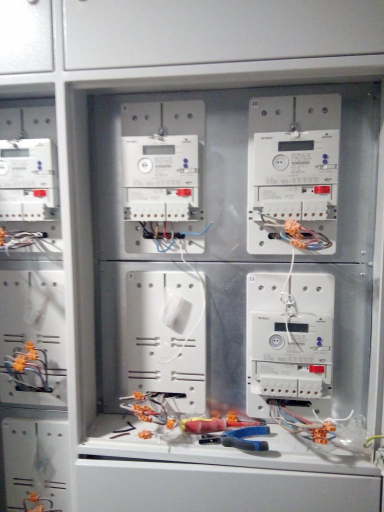 Wnętrze rozdzielnicy z zamontowanymi licznikami energii elektrycznej, widoczne przewody, złączki Wago i narzędzia - szczypce i śrubokręt.