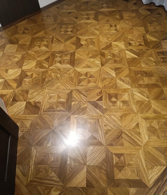 Wzorzysta podłoga z parkietu w Mętowie. Geometryczny układ klepek tworzy unikalny design, z delikatnym połyskiem podkreślającym naturalne drewno.