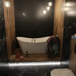 Nowoczesna łazienka z wolnostojącą wanną na podeście, czarne płytki imitujące marmur z białymi żyłami, drewnopodobne panele na ścianach, oświetlenie punktowe i podświetlenie LED pod podestem.