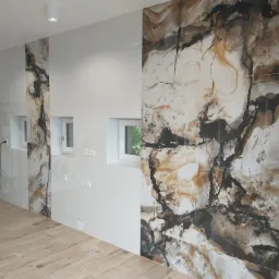 Wykończona łazienka z płytkami imitującymi marmur na ścianie, jasnymi panelami podłogowymi i widoczną instalacją wodną oraz pralką w rogu.