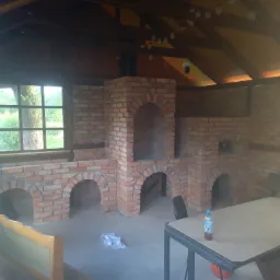 Murowana konstrukcja z cegły z łukowymi otworami w zadaszonej przestrzeni, widok z boku, oświetlenie naturalne