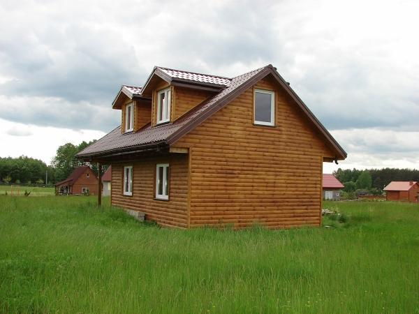 Nowoczesny, parterowy dom z brązową elewacją w Harrow, otoczony wysoką trawą i innymi budynkami w tle.