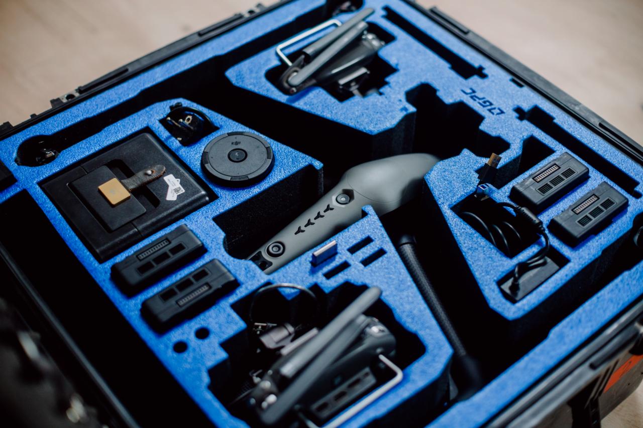 Zestaw drona DJI w sztywnym futerale z wyprofilowaną, niebieską pianką, zawierający kontroler, zapasowe akumulatory i akcesoria.