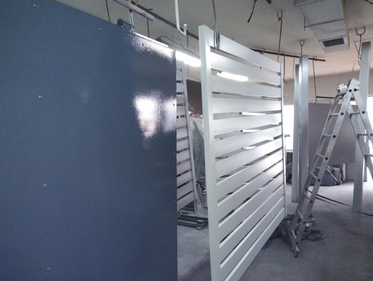 Brama wjazdowa lamelowa w trakcie malowania proszkowego, widoczna drabina i elementy konstrukcyjne w tle.