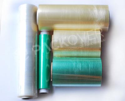 Zestaw rolek folii stretch w różnych kolorach (biały, zielony, beżowy) ułożonych na białym tle, widoczne napisy na niektórych rolkach.