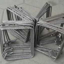 Stos kwadratowych i prostokątnych elementów z giętej stali, ułożonych w grupach na szarym tle posadzki.