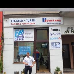 ArturBau - Fasada firmy Artur Fenster, polskiego producenta okien i drzwi, z właścicielem pozującym przed wejściem, na witrynie widoczne logo firmy oraz informacje o ofercie i producenci profili.