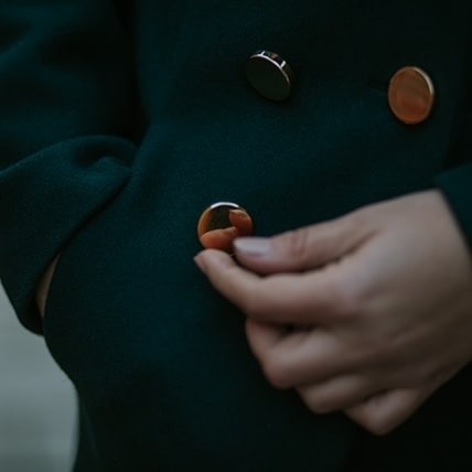 Szmaragdowy płaszcz z ręką zapinającą okrągły, złoty guzik.