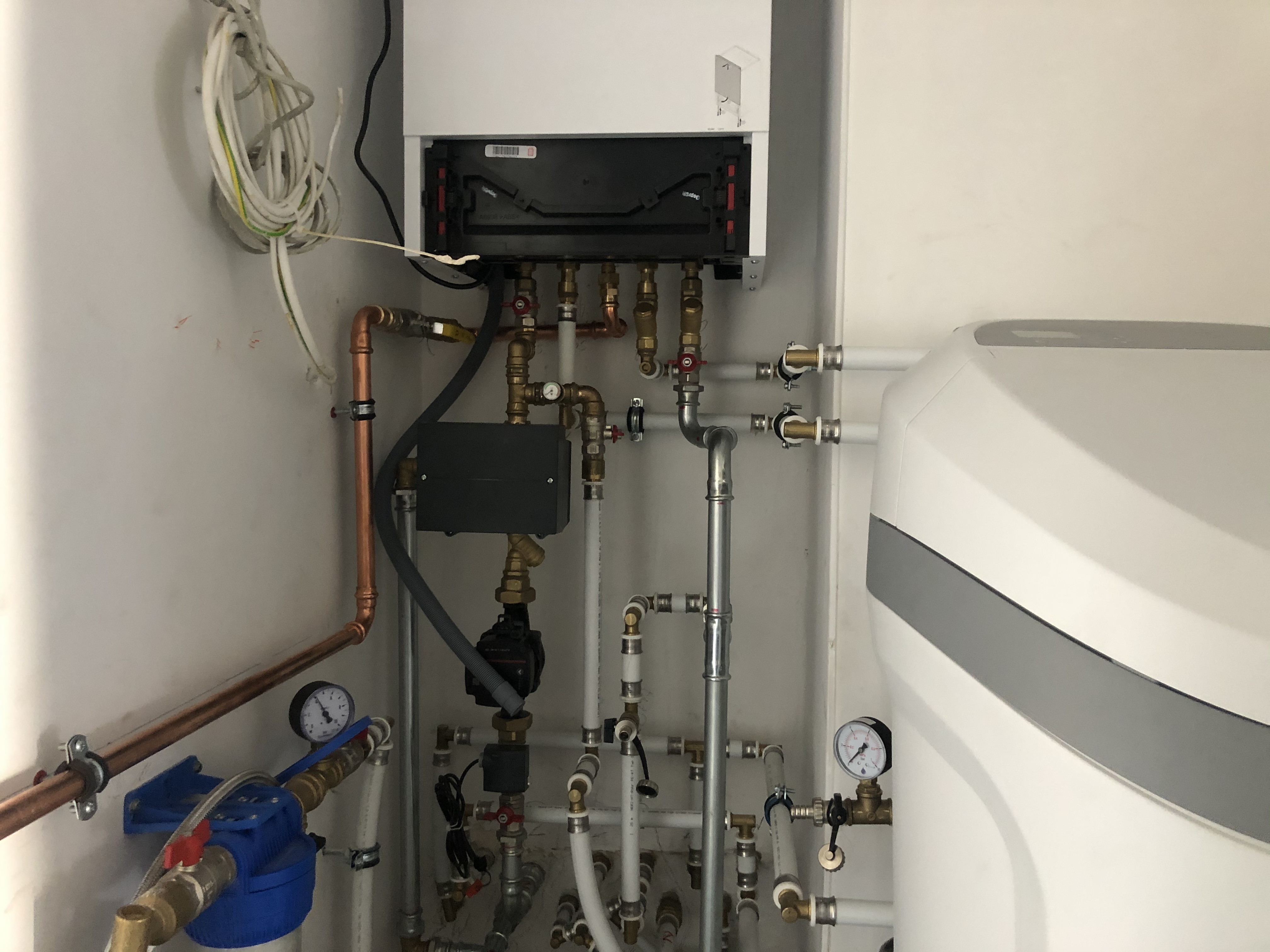 Węzeł cieplny z piecem gazowym, pompą obiegową, filtrem wody i zmiękczaczem wody, liczne rury miedziane i plastikowe, manometry
