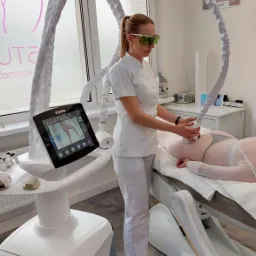 Kobieta w okularach ochronnych wykonuje zabieg na ciele pacjentki przy użyciu urządzenia Icone Laser C w gabinecie kosmetycznym.