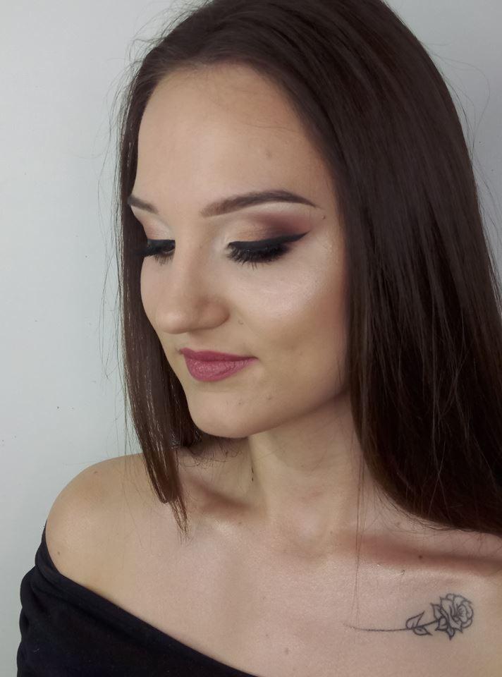 Portret kobiety z profesjonalnym makijażem oczu w odcieniach brązu i czarną kreską, delikatną różową szminką i tatuażem róży na obojczyku.
