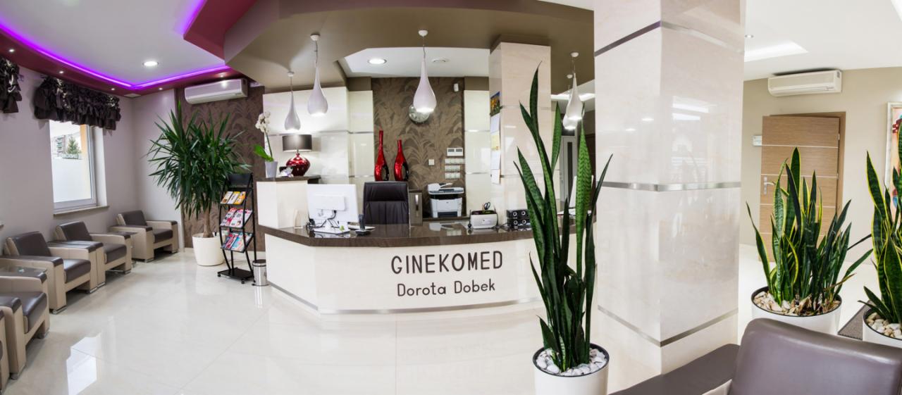 Jasne, przestronne wnętrze kliniki z recepcją z napisem 'GINEKOMED Dorota Dobek', roślinami doniczkowymi i poczekalnią z fotelami.