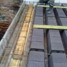 Budowa stropu Teriva: ułożone betonowe pustaki stropowe na deskowaniu zbrojonym stalą, widoczny pracownik w roboczym ubraniu.