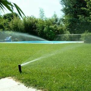 Działający system nawadniania trawnika w Glinianka, zraszacz w akcji, w tle widoczny basen i zieleń ogrodu.