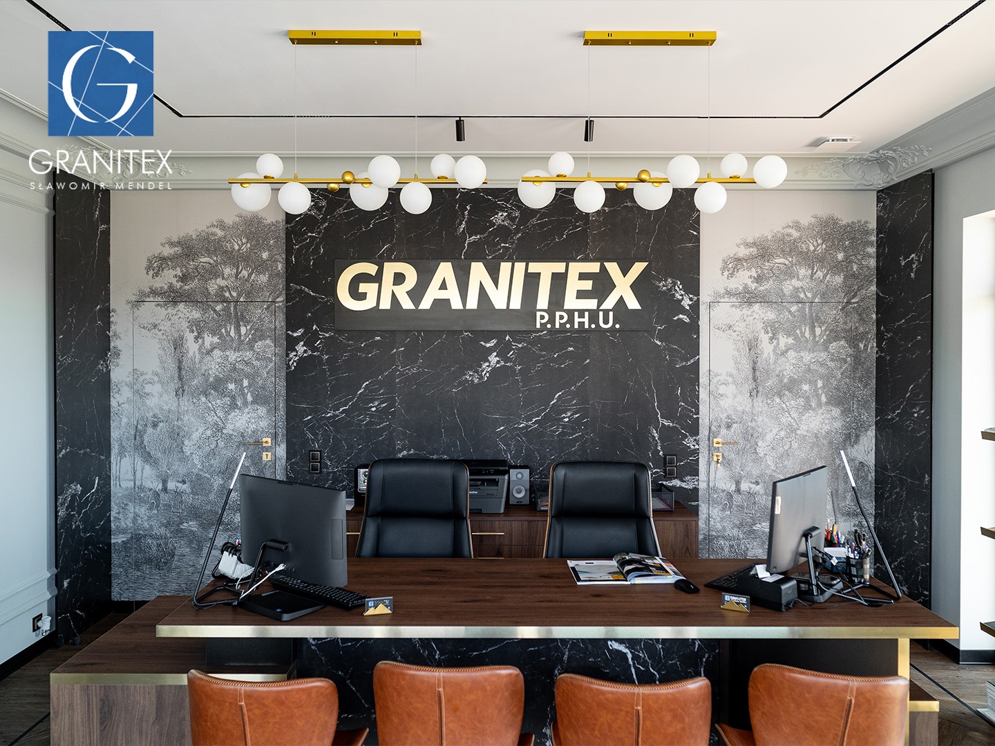 Eleganckie biuro firmy Granitex z marmurowymi ścianami, drewnianym biurkiem i skórzanymi krzesłami. Widoczne logo firmy i designerskie oświetlenie.