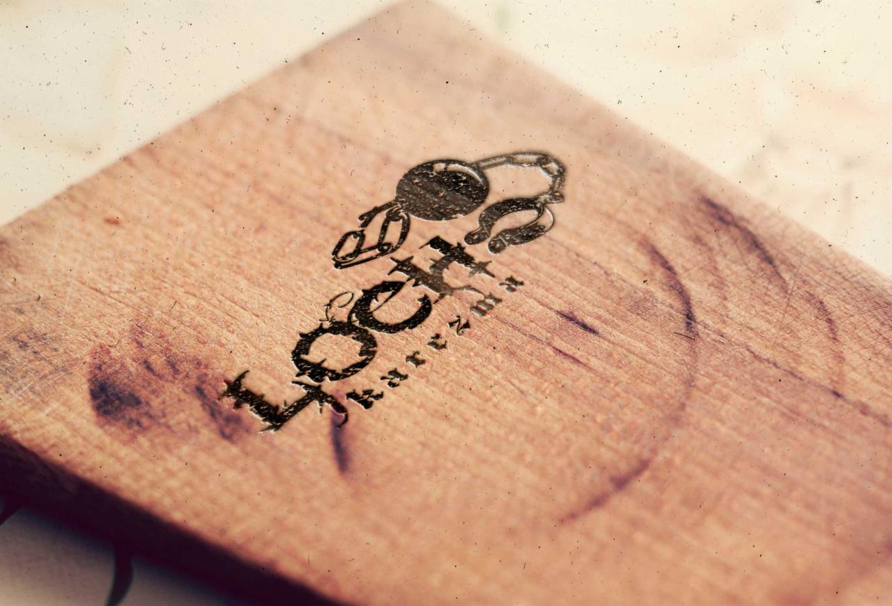 Drewniana deska z wygrawerowanym logo firmy i motywem klucza na łańcuszku, widoczne ślady użytkowania.