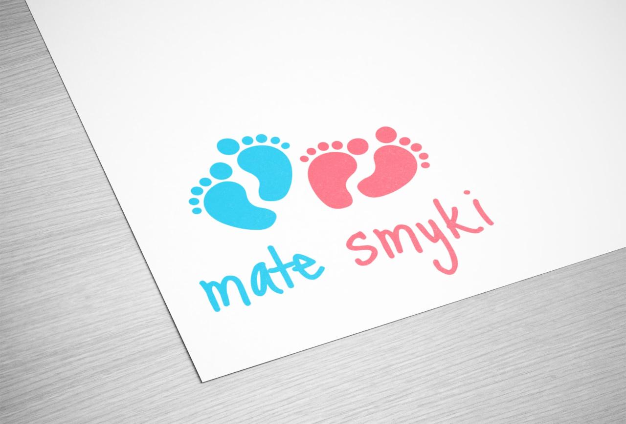 Logo firmy 'mate smyki' z niebieskimi i różowymi odciskami stóp na białym papierze z delikatną teksturą drewna w tle.