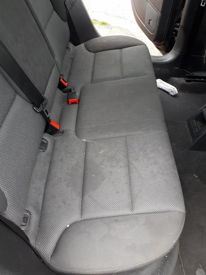 Brudna, szara tylna kanapa samochodowa przed czyszczeniem, widoczne plamy i zabrudzenia na tapicerce, usługa dostępna w Zielonej Górze.