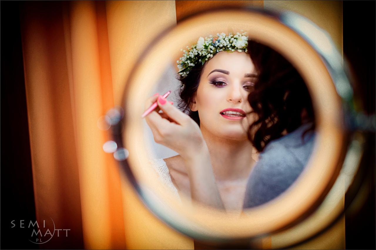 Panna młoda z wiankiem na głowie, malująca brwi przed lustrem z oświetleniem ring light, przygotowania do ślubu.