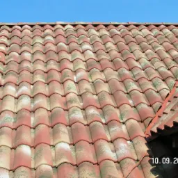 Czerwono-beżowa dachówka ceramiczna typu mnich-zakonnica na dachu domu, widoczny fragment dachu z datą wykonania 10.09.2009.