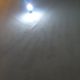 USŁUGI OGÓLNOBUDOWLANE KEN-BUD MACIEJ KĘDZIERSKI - Szara ściana z widocznym oświetleniem sufitowym, ukazująca strukturę powierzchni.