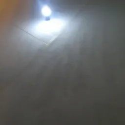 Szara ściana z widocznym oświetleniem sufitowym, ukazująca strukturę powierzchni.