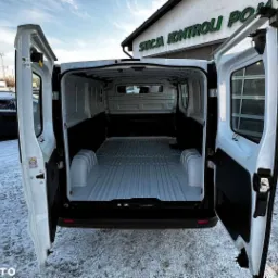 Wnętrze paki białego busa dostawczego z otwartymi drzwiami na zewnątrz na tle ośnieżonego terenu.