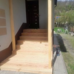 F.H.U CIESIELSKI PIOTR - Drewniany taras z schodami w trakcie budowy. Widoczne narzędzia, elementy konstrukcji i krajobraz w tle. Świeże drewno, jasne oświetlenie.