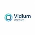 Logo firmy Vidium Medica z abstrakcyjnym, okrągłym symbolem w odcieniach błękitu i zieleni po lewej stronie nazwy. Tekst 'Vidium' umieszczony nad słowem 'medica'.