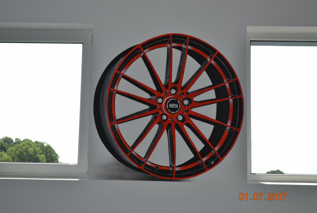 Mural przedstawiający felgę samochodową DOTZ w kolorze czerwono-czarnym, namalowany na szarej ścianie między dwoma oknami, z datą 01.07.2017 w prawym dolnym rogu.