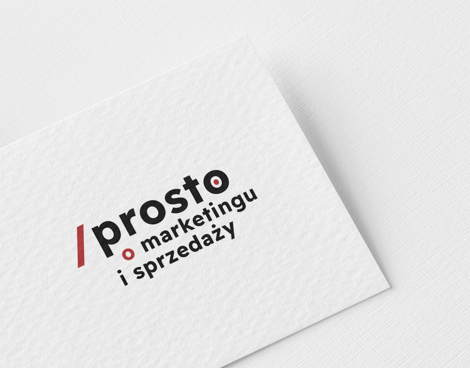 Logo firmy '/prosto o marketingu i sprzedaży' na białym, teksturowanym papierze, ułożone pod kątem.