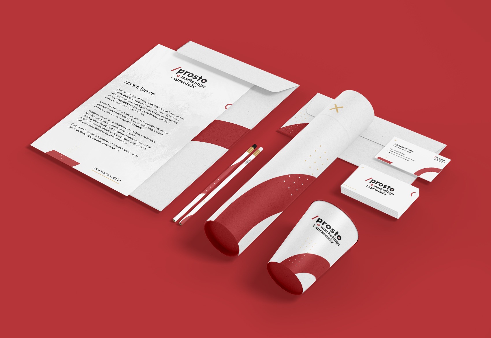 Zestaw materiałów identyfikacji wizualnej na czerwonym tle: papier firmowy, koperta, wizytówki, tuba i dwa ołówki z brandingiem '/prosto o marketingu i sprzedaży'.