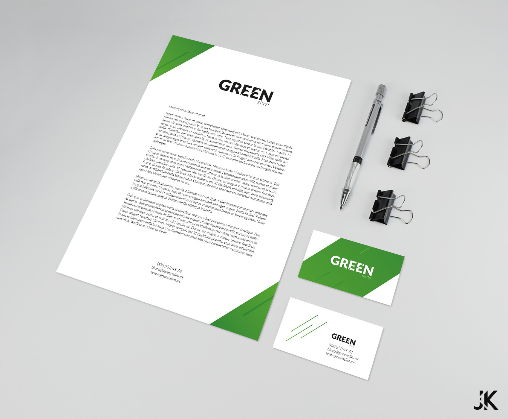 Mockup papieru firmowego i wizytówki z zielonym akcentem, leżące obok ołówka automatycznego i spinaczy biurowych na jasnym tle.
