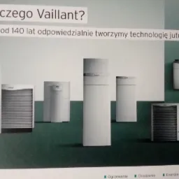 Ekspozycja różnych modeli urządzeń grzewczych i klimatyzacyjnych marki Vaillant na tle zielono-białej ściany z hasłem reklamowym.