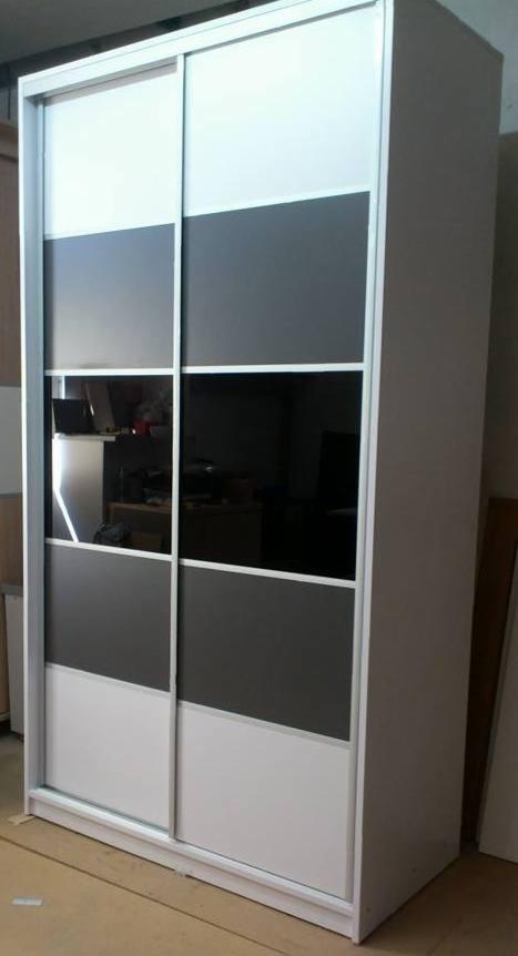 Biało-szara szafa przesuwna z panelami lustrzanymi, widoczne odbicie wnętrza pomieszczenia.