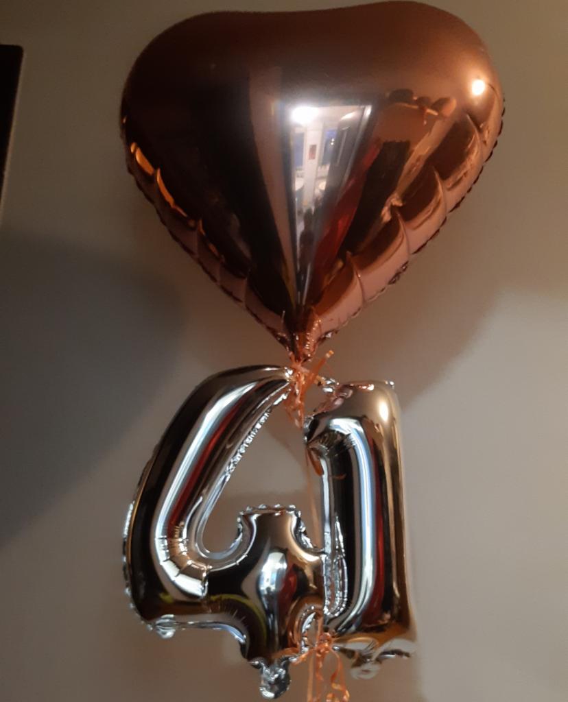 Balony foliowe w kształcie cyfr '4' i '1' oraz balon w kształcie serca w kolorze różowego złota, zawieszone na tle jasnej ściany.